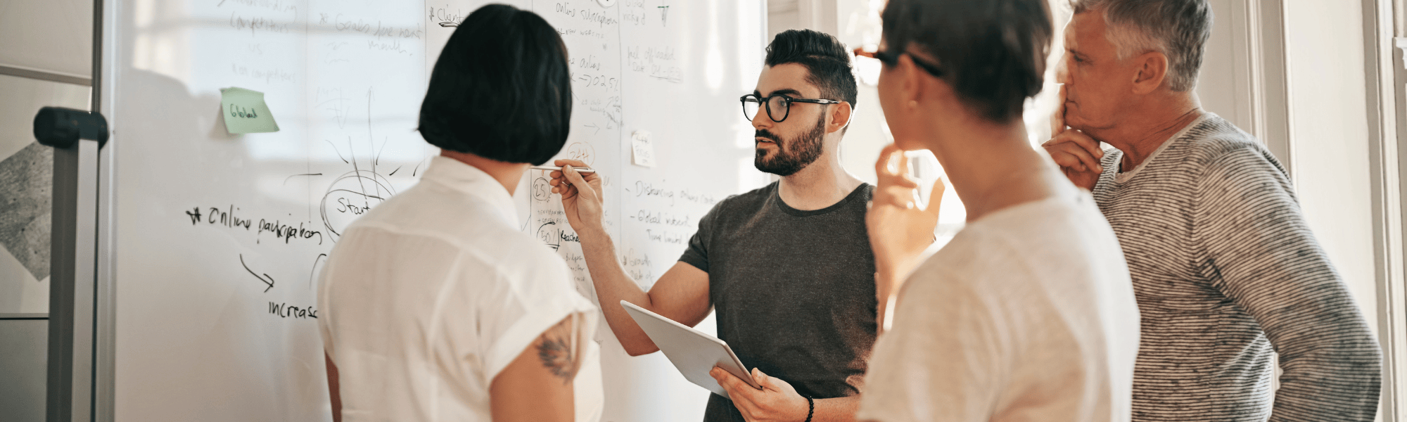 A group of professionals brainstorming and discussing ideas in a meeting room with a whiteboard, highlighting teamwork and business strategy for growth and success.