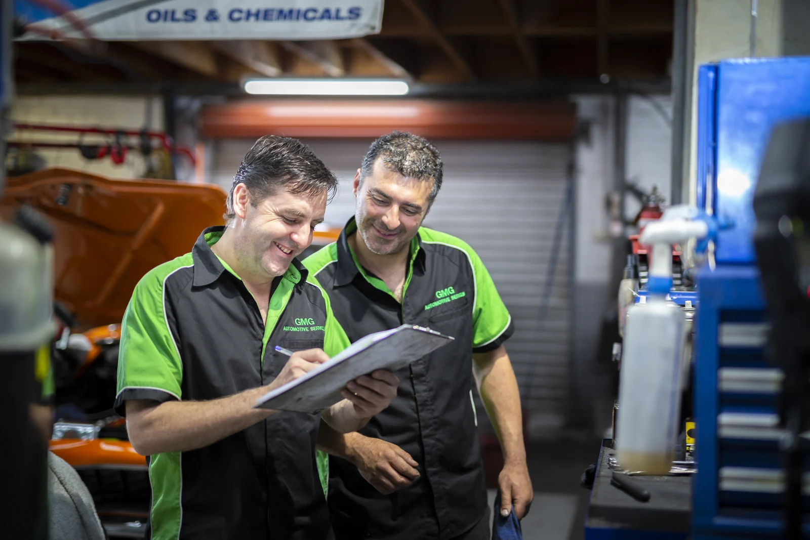 Two GMG mechanics going over a job sheet together on the workshop floor