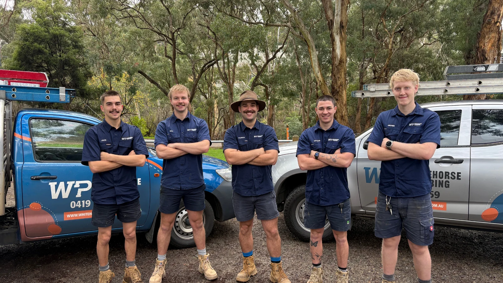 The Whitehorse Plumbing team standing in front of their branded utes